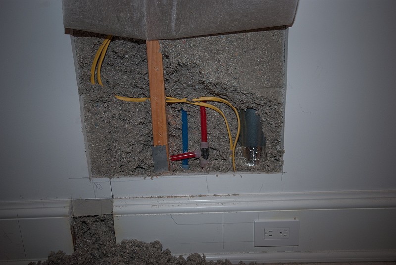 DSC_2798.jpg - Kris alerted me to the need to move an electrical outlet out of the way of a new partition going into bonus room entry hall.  "Sure" I thought, "how hard can that be?"  It turns out that within the short 16-inch move to the right I ran into hot and cold PEX lines and the dryer vent duct for the adjacent laundry.  I worked everything out as shown here and the carpentry could proceed.  I added another steel nail plate to the stud to protect the electrical wires before the sheetrock was replaced.